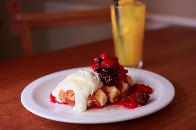 A Belgian waffle with cream and berry compote