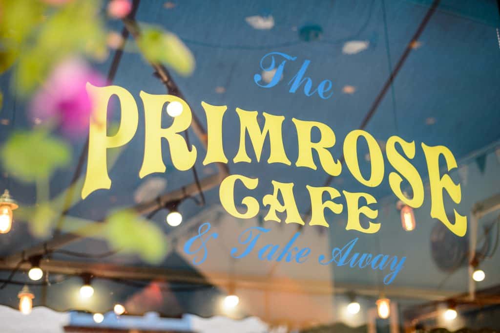 Close view of the painted Primrose Cafe sign with greenery